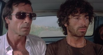 Movie still from “Rabid Dogs” (1974), directed by Mario Bava – Two men sitting in the back seat of a car; Close Up shot, Low angle