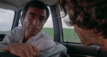 Movie still from “Rabid Dogs” (1974), directed by Mario Bava – A man sitting in the back seat of a car looking at another man; Close Up shot, Over the shoulder angle