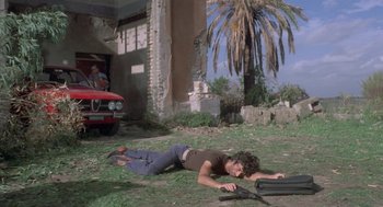 Movie still from “Rabid Dogs” (1974), directed by Mario Bava – A woman laying on the ground in a yard; Wide shot, Low angle