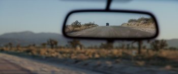 Movie still from “Race to Witch Mountain” (2009), directed by Andy Fickman – A rear view mirror of a car driving down a road; Extreme Wide shot, Over the shoulder angle