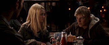 Movie still from “Race to Witch Mountain” (2009), directed by Andy Fickman – Two people sitting at a table in front of a bottle; Medium shot, Over the shoulder angle