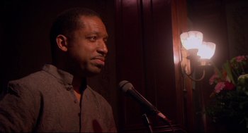 Movie still from “Rachel Getting Married” (2008), directed by Jonathan Demme – A man standing in front of a microphone in a room; Close Up shot, Low angle
