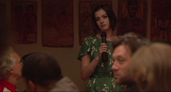 Movie still from “Rachel Getting Married” (2008), directed by Jonathan Demme – A woman in a green dress is holding a microphone; Medium shot, Over the shoulder angle