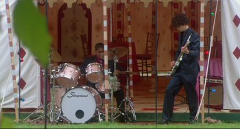 Movie still from “Rachel Getting Married” (2008), directed by Jonathan Demme – Two men playing drums and a guitar in front of a tent; Wide shot, Over the shoulder angle