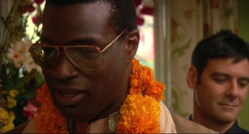 Movie still from “Rachel Getting Married” (2008), directed by Jonathan Demme – A person wearing glasses and a flower lei; Close Up shot, Over the shoulder angle