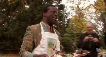 Movie still from “Rachel Getting Married” (2008), directed by Jonathan Demme – A man wearing an apron is cooking on a grill outside; Medium shot, Over the shoulder angle