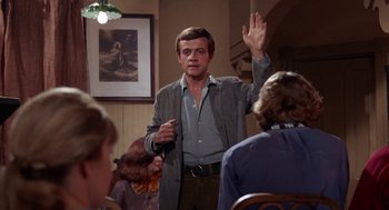 Movie still from “Rachel, Rachel” (1968), directed by Paul Newman – A man is standing up in front of a group of people; Medium shot, Over the shoulder angle