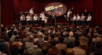 Movie still from “Radio Days” (1987), directed by Woody Allen – A man in a suit is speaking to a crowd of people; Wide shot, High angle