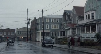 Movie still from “Radio Days” (1987), directed by Woody Allen – A car parked on the side of the road in the rain; Extreme Wide shot, High angle