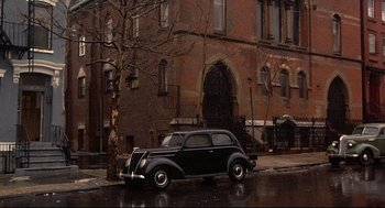 Movie still from “Radio Days” (1987), directed by Woody Allen – An old car parked on the side of the street; Extreme Wide shot, High angle