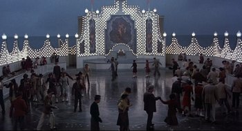 Movie still from “Radio Days” (1987), directed by Woody Allen – A group of people standing in front of a building with lights; Extreme Wide shot, High angle