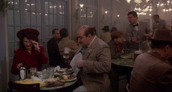 Movie still from “Radio Days” (1987), directed by Woody Allen – A group of people sitting at a table with food; Medium shot, Over the shoulder angle