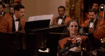 Movie still from “Radio Days” (1987), directed by Woody Allen – A woman holding a white dog in front of a piano; Medium shot, Over the shoulder angle