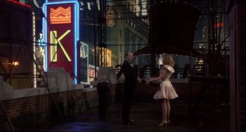 Movie still from “Radio Days” (1987), directed by Woody Allen – A man and a woman are shaking hands in front of a neon sign; Wide shot, Over the shoulder angle