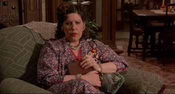 Movie still from “Radio Days” (1987), directed by Woody Allen – A woman sitting on a couch holding a book; Medium shot, High angle