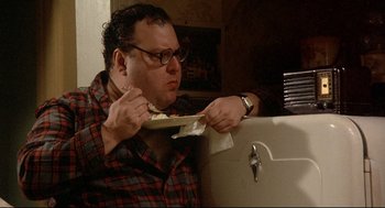 A man eating a piece of food while sitting in a chair
