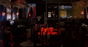 Movie still from “Radio Days” (1987), directed by Woody Allen – A room with a red table and chairs and a staircase in the background; Wide shot, High angle