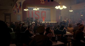 Movie still from “Radio Days” (1987), directed by Woody Allen – A crowd of people sitting at tables in front of a stage; Extreme Wide shot, High angle