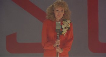 Movie still from “Radio Days” (1987), directed by Woody Allen – A woman in a red dress holding a microphone; Close Up shot, Low angle