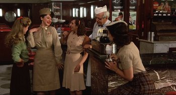 Movie still from “Radio Days” (1987), directed by Woody Allen – A group of people standing around a bar; Medium shot, Over the shoulder angle