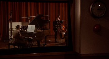 Movie still from “Radio Days” (1987), directed by Woody Allen – A man playing the piano and a cello in front of a piano; Wide shot, High angle