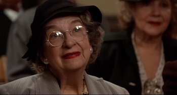 Movie still from “Radio Days” (1987), directed by Woody Allen – An older woman wearing glasses and a black hat; Close Up shot, Over the shoulder angle