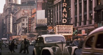 Movie still from “Radio Days” (1987), directed by Woody Allen – A car driving down a street next to buildings; Extreme Wide shot, High angle
