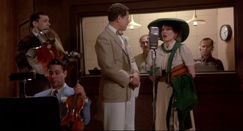 Movie still from “Radio Days” (1987), directed by Woody Allen – A man and a woman sing in front of a microphone; Medium shot, Over the shoulder angle