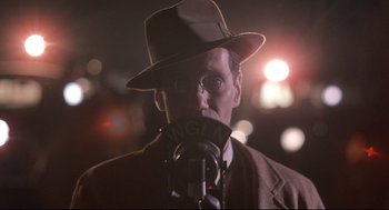 Movie still from “Radio Days” (1987), directed by Woody Allen – A man in a hat and glasses is talking into a microphone; Close Up shot, Low angle