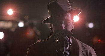 Movie still from “Radio Days” (1987), directed by Woody Allen – A man in a hat is talking into a microphone; Close Up shot, Low angle