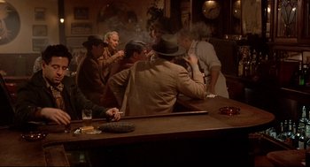 Movie still from “Radio Days” (1987), directed by Woody Allen – A group of men sitting at a bar smoking cigarettes; Wide shot, High angle