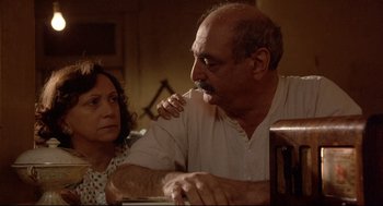 Movie still from “Radio Days” (1987), directed by Woody Allen – An older man and a younger woman sitting at a table; Medium shot, High angle