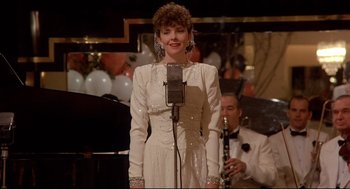 A woman in a white dress singing into a microphone