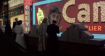 Movie still from “Radio Days” (1987), directed by Woody Allen – Two people are standing in front of a neon sign; Wide shot, Low angle