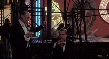 Movie still from “Radio Days” (1987), directed by Woody Allen – A man in a tuxedo sitting next to another man in a suit; Medium shot, Low angle