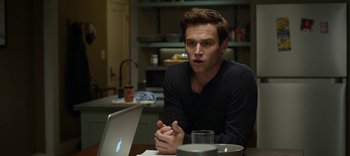 Movie still from “13 Reasons Why” (2017), created by Brian Yorkey – A man sitting in front of an open laptop computer on top of a wooden table; Close Up shot, Over the shoulder angle