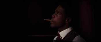Movie still from “Ragtime” (1981), directed by Milos Forman – A man in a suit smoking a cigarette; Close Up shot, Low angle