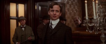 Movie still from “Ragtime” (1981), directed by Milos Forman – A man in a suit and tie standing in front of a group of people; Close Up shot, Low angle