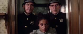 Movie still from “Ragtime” (1981), directed by Milos Forman – Three police officers standing next to a woman in a car; Close Up shot, Low angle