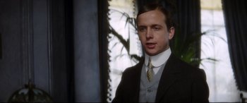 Movie still from “Ragtime” (1981), directed by Milos Forman – A man in a suit and tie standing in front of a window; Close Up shot, Low angle