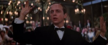 Movie still from “Ragtime” (1981), directed by Milos Forman – A man in a black suit and bow tie holding a wii controller; Close Up shot, Low angle