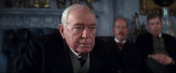 Movie still from “Ragtime” (1981), directed by Milos Forman – An older man wearing a suit and tie; Close Up shot, Over the shoulder angle