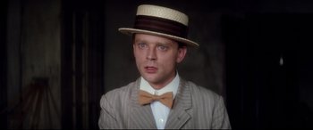 Movie still from “Ragtime” (1981), directed by Milos Forman – A man wearing a hat and a bow tie; Close Up shot, Low angle