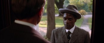 Movie still from “Ragtime” (1981), directed by Milos Forman – A man wearing a suit and hat talking to another man in a suit; Close Up shot, Over the shoulder angle