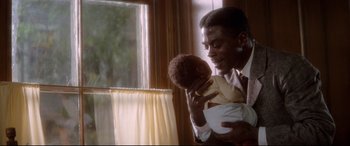Movie still from “Ragtime” (1981), directed by Milos Forman – A man holding a baby in his arms in front of a window; Medium shot, High angle