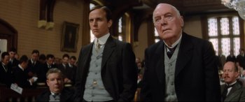 Movie still from “Ragtime” (1981), directed by Milos Forman – A man and a man standing next to each other in a room; Medium shot, Low angle