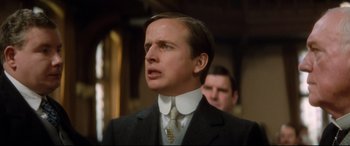 Movie still from “Ragtime” (1981), directed by Milos Forman – A man wearing a suit and tie in a room; Close Up shot, Low angle