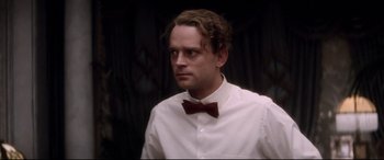 Movie still from “Ragtime” (1981), directed by Milos Forman – A man in a white shirt and a red bow tie; Close Up shot, Low angle