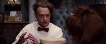 Movie still from “Ragtime” (1981), directed by Milos Forman – A man wearing a bow tie sitting at a table; Close Up shot, Over the shoulder angle
