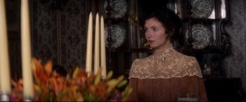 Movie still from “Ragtime” (1981), directed by Milos Forman – A woman standing in front of a table with candles; Medium shot, Over the shoulder angle